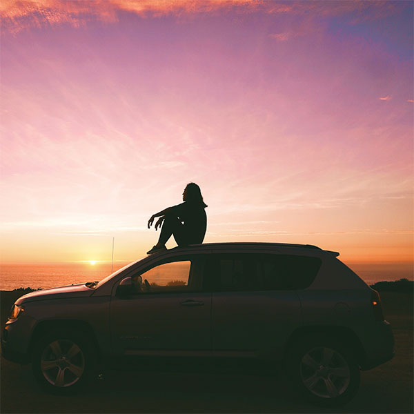 Person on top of car at sunset