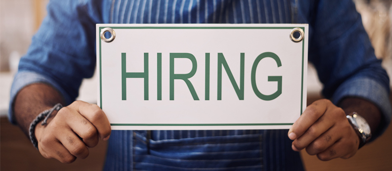 Business owner holding a hiring sign